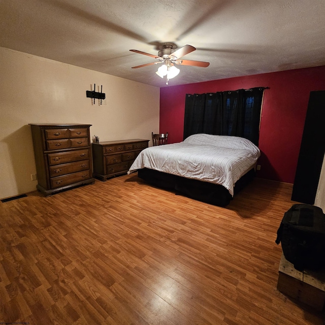 bedroom with hardwood / wood-style flooring, a textured ceiling, and ceiling fan