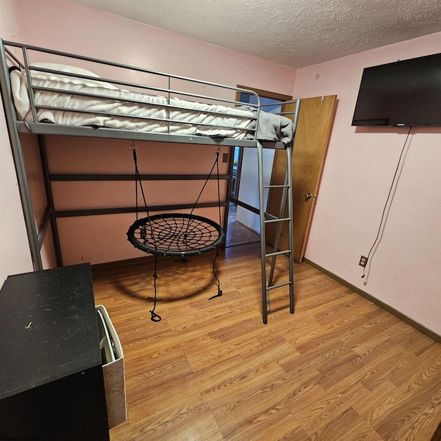 bedroom with light hardwood / wood-style floors and a textured ceiling