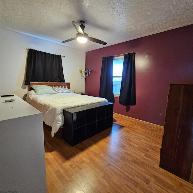 bedroom with hardwood / wood-style flooring, a textured ceiling, and ceiling fan