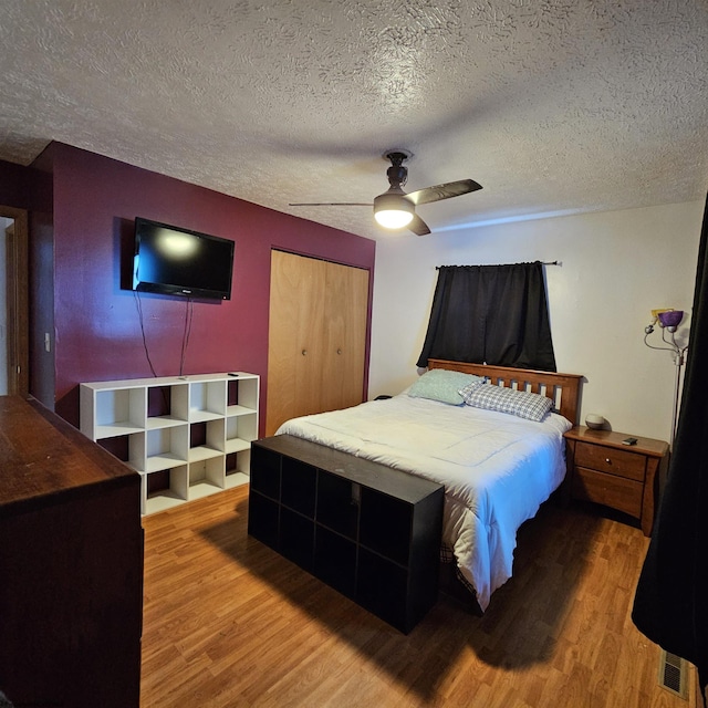 bedroom with hardwood / wood-style floors, a textured ceiling, a closet, and ceiling fan