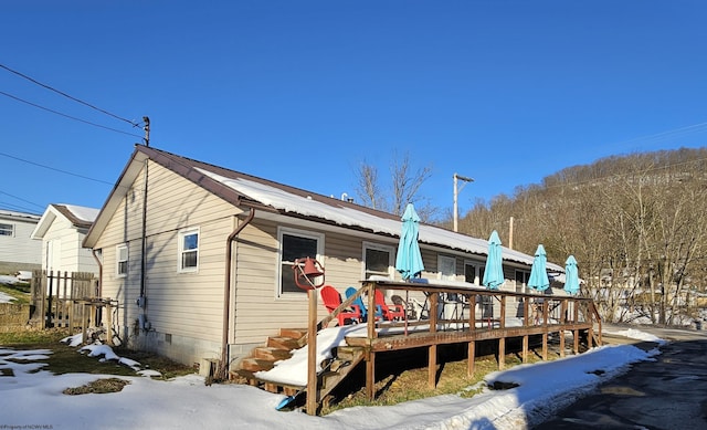 snow covered back of property featuring a deck