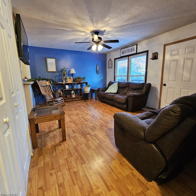 living room featuring ceiling fan, a textured ceiling, and light hardwood / wood-style floors