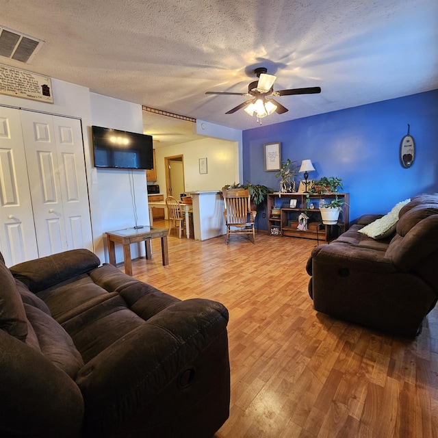 living room with ceiling fan, hardwood / wood-style floors, and a textured ceiling