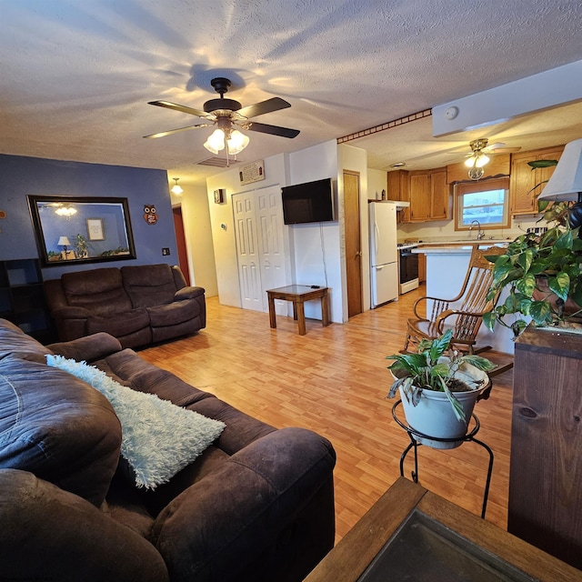 living room with sink, a textured ceiling, ceiling fan, and light hardwood / wood-style flooring