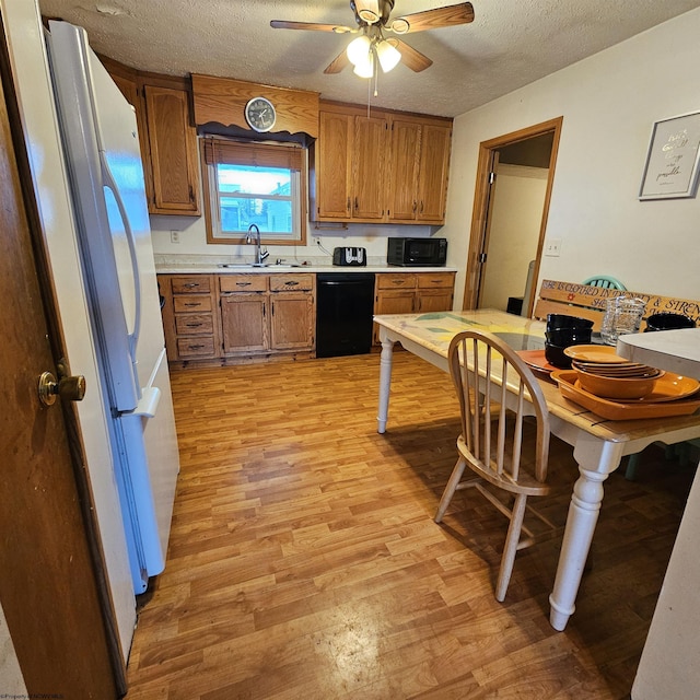 kitchen featuring black appliances, sink, ceiling fan, light hardwood / wood-style floors, and a textured ceiling