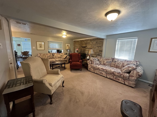 living room with a stone fireplace, a textured ceiling, and carpet flooring