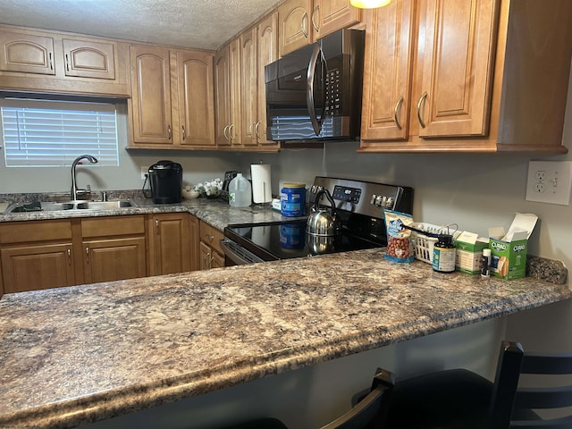 kitchen featuring sink, electric range, a kitchen breakfast bar, a textured ceiling, and dark stone counters