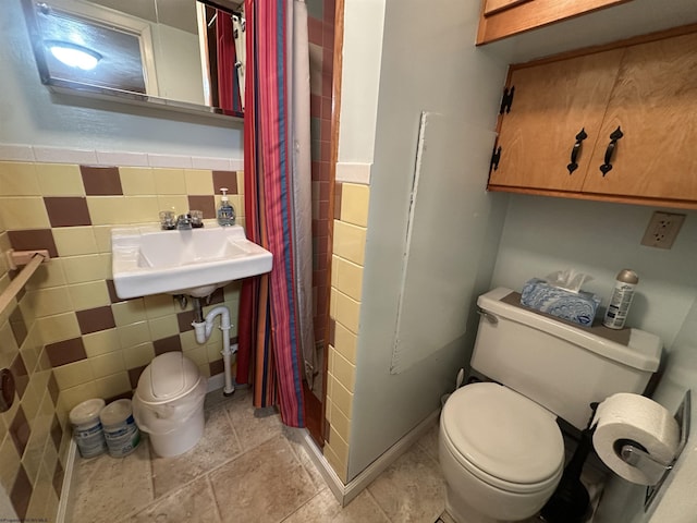 bathroom with toilet, sink, and tile walls