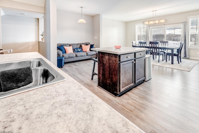 kitchen featuring pendant lighting, sink, a kitchen breakfast bar, dark brown cabinetry, and a kitchen island