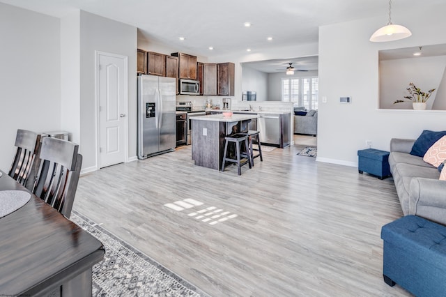 living room with sink, ceiling fan, and light wood-type flooring