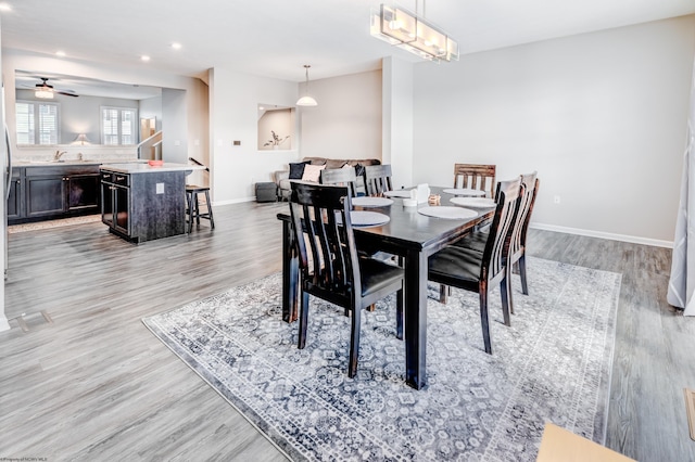 dining area featuring ceiling fan, sink, and light wood-type flooring