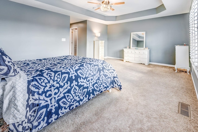 bedroom with ceiling fan, a tray ceiling, and carpet floors