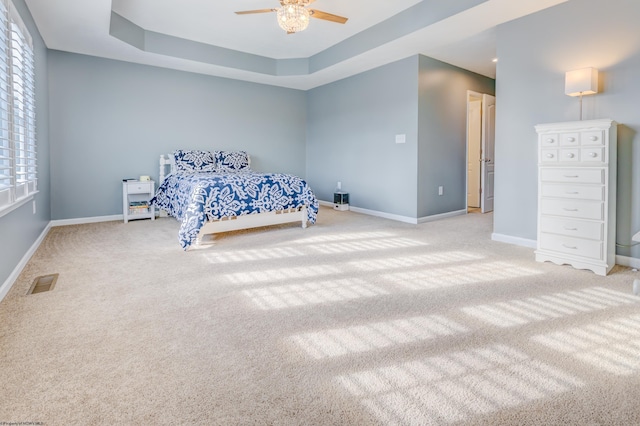 unfurnished bedroom featuring light colored carpet, a raised ceiling, and ceiling fan