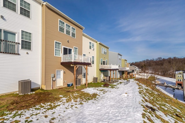 snow covered property with cooling unit and a balcony