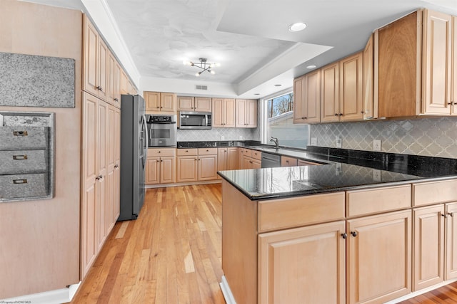 kitchen featuring appliances with stainless steel finishes, light brown cabinetry, sink, light hardwood / wood-style floors, and a raised ceiling