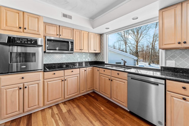 kitchen with sink, dark hardwood / wood-style floors, stainless steel appliances, and dark stone counters