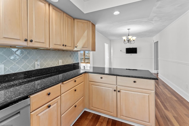 kitchen featuring decorative light fixtures, dark hardwood / wood-style flooring, dark stone counters, stainless steel dishwasher, and kitchen peninsula