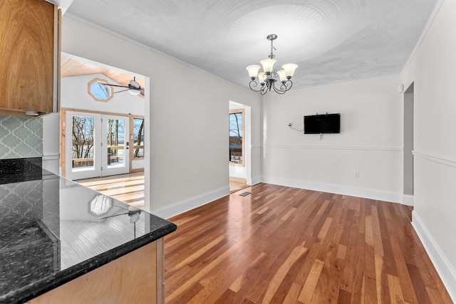 unfurnished dining area featuring ceiling fan with notable chandelier and hardwood / wood-style floors