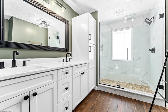 bathroom featuring vanity, a shower with shower door, and a textured ceiling