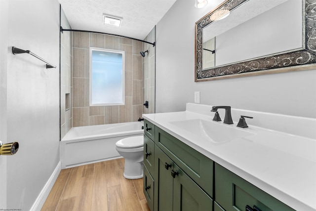 full bathroom with toilet, tiled shower / bath, wood-type flooring, a textured ceiling, and vanity