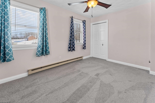 empty room featuring a baseboard heating unit, plenty of natural light, ceiling fan, and carpet flooring