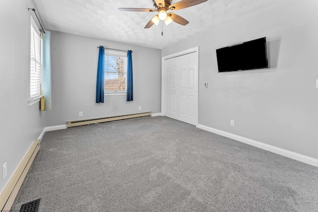 carpeted empty room with ceiling fan and baseboard heating