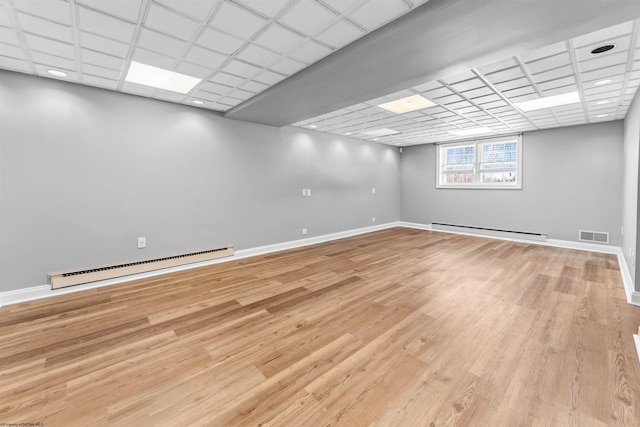 basement with a baseboard heating unit and light wood-type flooring