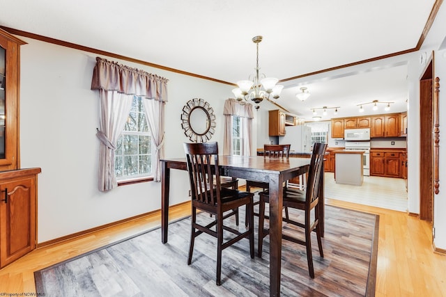 dining area with ornamental molding, a chandelier, and light wood-type flooring