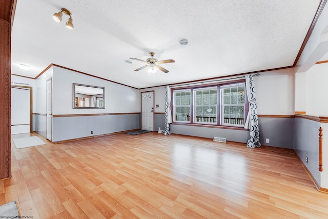 unfurnished living room with crown molding, ceiling fan, and light wood-type flooring