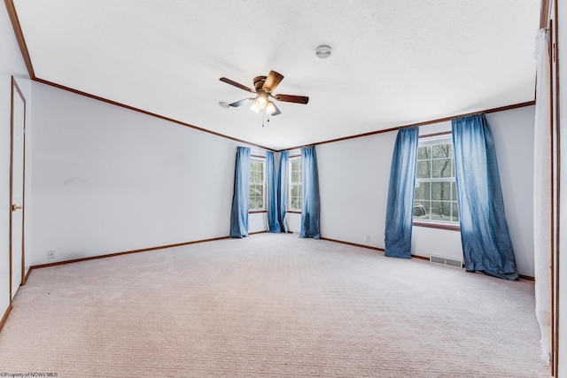 carpeted empty room featuring crown molding, a healthy amount of sunlight, and ceiling fan