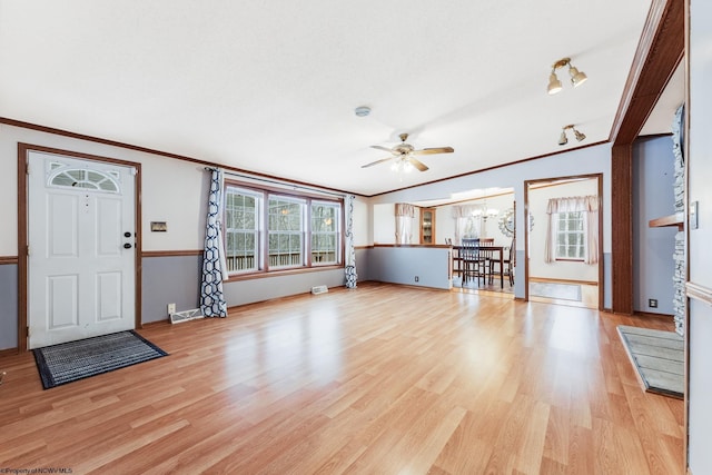 unfurnished living room featuring ornamental molding, ceiling fan with notable chandelier, and light hardwood / wood-style flooring