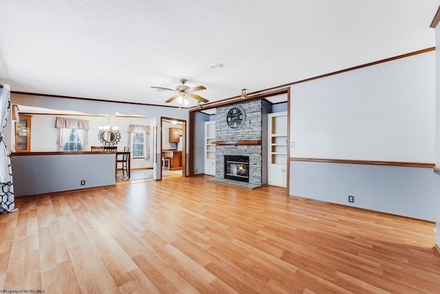 unfurnished living room with a stone fireplace, ceiling fan with notable chandelier, ornamental molding, light hardwood / wood-style floors, and a textured ceiling