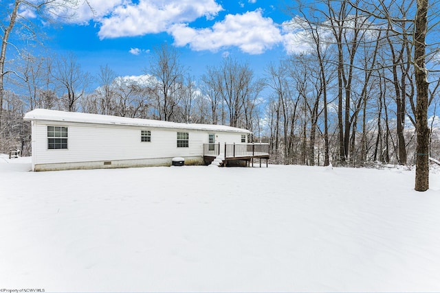 snow covered rear of property with a wooden deck