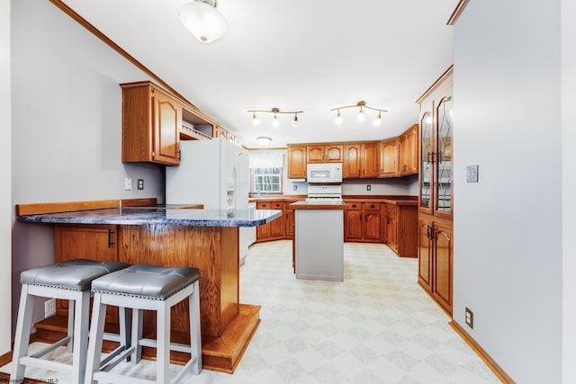 kitchen featuring white appliances, a breakfast bar, kitchen peninsula, and a kitchen island