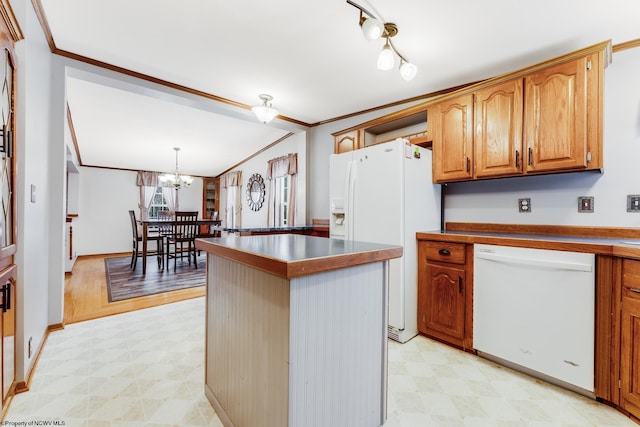 kitchen with white appliances, ornamental molding, a center island, and hanging light fixtures