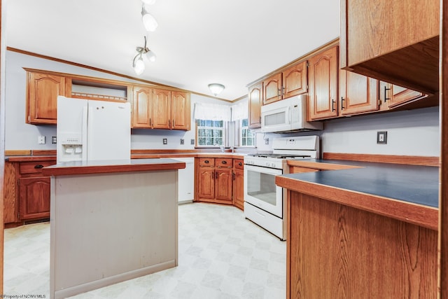 kitchen featuring lofted ceiling, sink, white appliances, crown molding, and a kitchen island