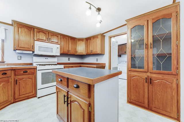 kitchen featuring white appliances, ornamental molding, a center island, and washer / dryer