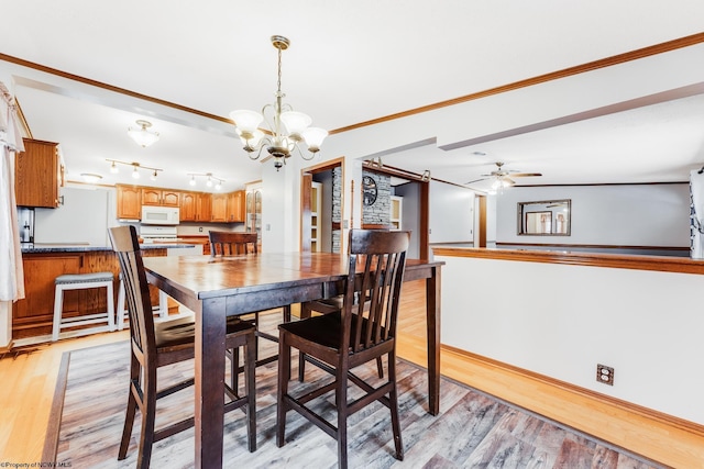 dining space with crown molding, ceiling fan with notable chandelier, and light wood-type flooring