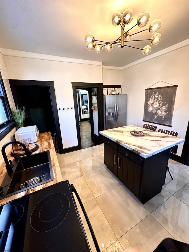 kitchen with a kitchen island, a breakfast bar, sink, stainless steel fridge, and ornamental molding