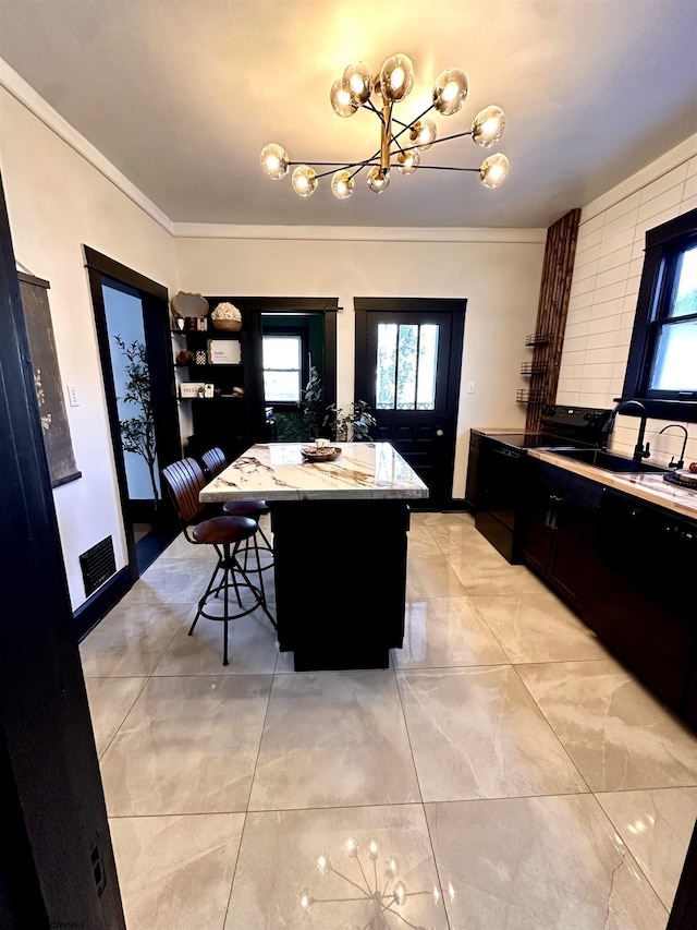 kitchen featuring a kitchen bar, crown molding, a kitchen island, pendant lighting, and light stone countertops