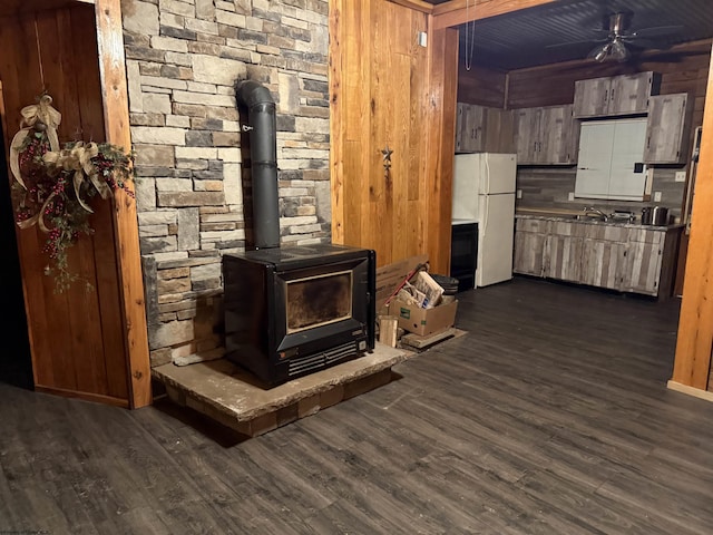 interior space featuring wood walls, wood-type flooring, white fridge, and a wood stove