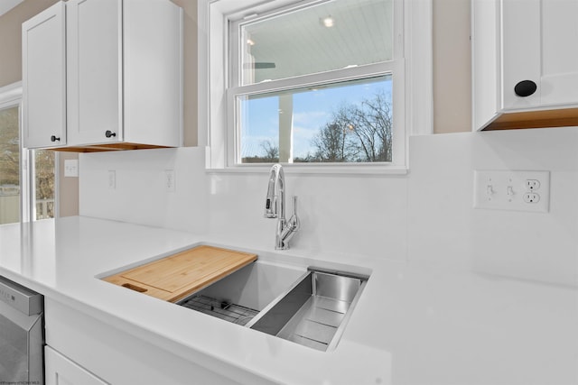 kitchen with dishwashing machine, sink, and white cabinets