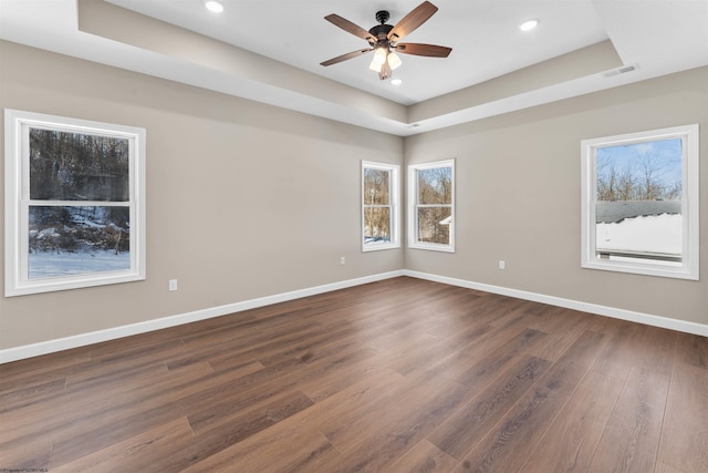 unfurnished room with a raised ceiling, ceiling fan, and dark hardwood / wood-style flooring