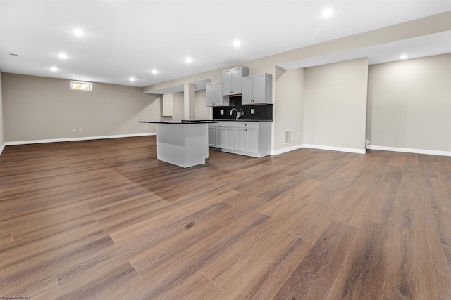 unfurnished living room with sink and light hardwood / wood-style floors