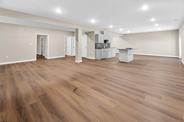 unfurnished living room featuring sink and light hardwood / wood-style flooring