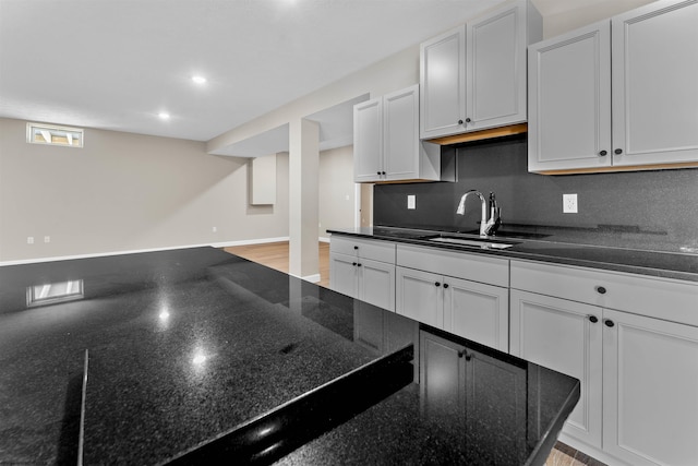 kitchen with white cabinetry, dark stone counters, sink, and tasteful backsplash