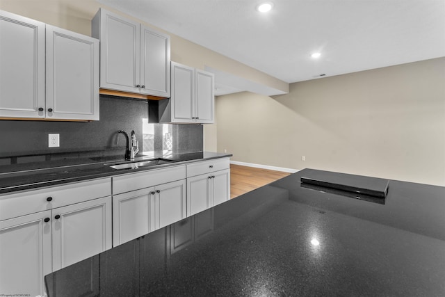 kitchen with white cabinets, sink, light hardwood / wood-style flooring, and backsplash