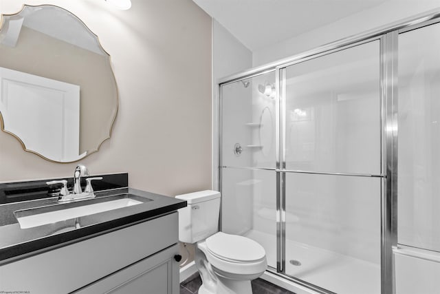 bathroom featuring vanity, toilet, and a shower with door