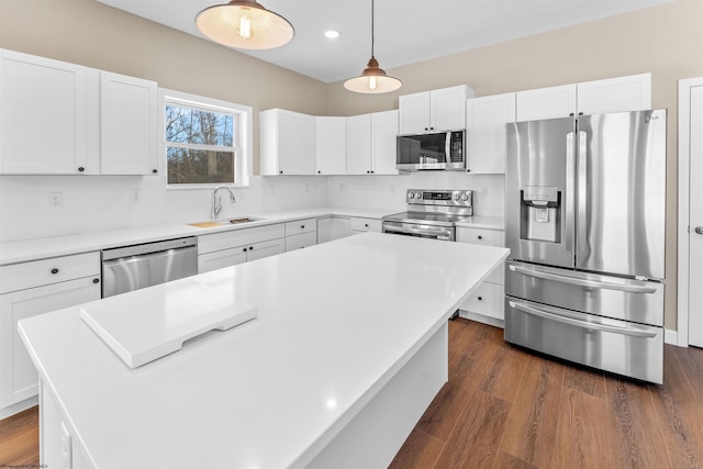 kitchen with a kitchen island, decorative light fixtures, white cabinetry, sink, and stainless steel appliances