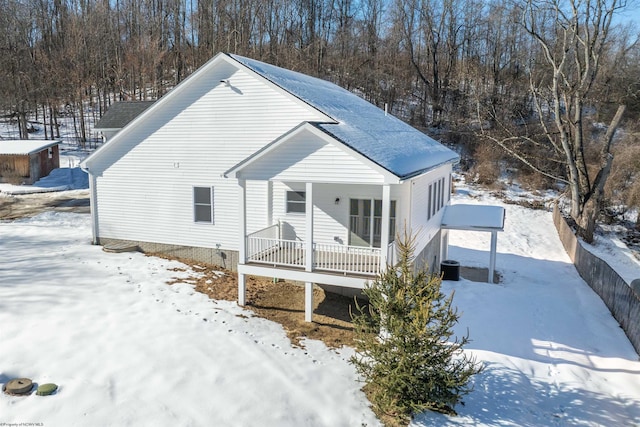 snow covered rear of property with a porch